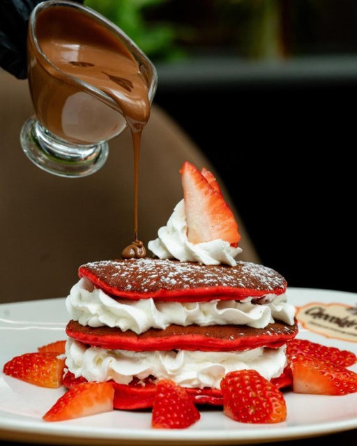 Red velvet pancake stack with chocolate sauce and strawberries
